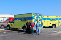Tres hombres parados junto a una camioneta de servicios médicos de emergencia